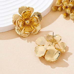 Detailed close-up of golden floral stud earrings with 3D layered petals on a stone base