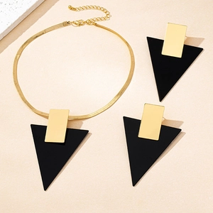 Detalle del conjunto de joyas geométricas doradas con colgantes triangulares negros y cadena