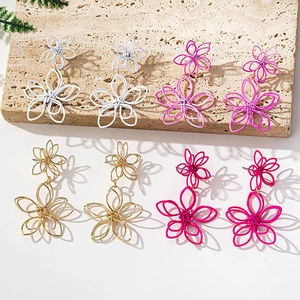 Detail of oversized geometric layered flower earrings in white purple gold and rose colors