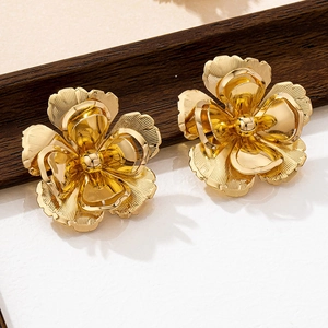 Macro detail of large golden flower stud earrings with layered metallic petals and texture