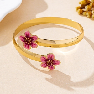 Détail du bracelet doré ouvert orné de fleurs de cerisier en émail rose poli