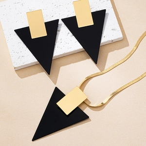 Primer plano de conjunto de joyas geométricas en negro y oro con collar y pendientes
