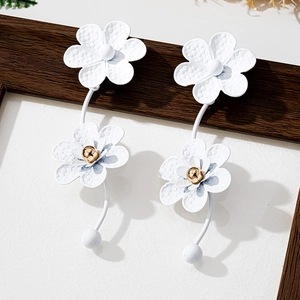 Detailed macro of white matte flower earrings with textured petals and golden stamen center