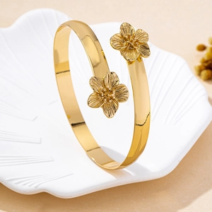 Détail de bracelets fleurs dorés avec pétales texturés dans un plat coquillage