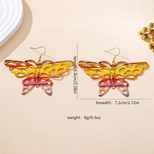 Macro shot of large butterfly dangle earrings featuring colorful gradient striped patterns