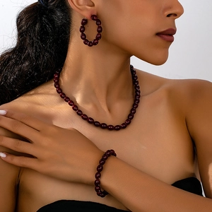 Vista detallada del conjunto de joyas rojo oscuro con collar, pulsera y pendientes