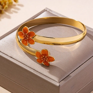 Gros plan détaillé d'un bracelet ouvert plaqué or avec motifs de fleurs en émail orange