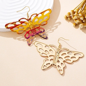 Macro shot of filigree butterfly earrings in gold and gradient colors on a beige display