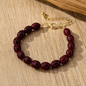 Detalle de pulsera con cuentas ovaladas burdeos y cierre de langosta dorado ajustable