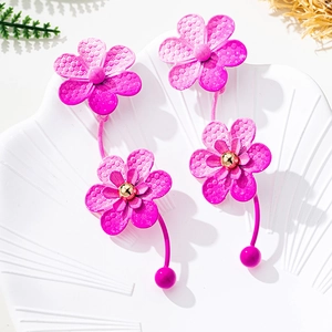 Detailed view of magenta flower earrings with double-layer petals and gold beads in shell tray
