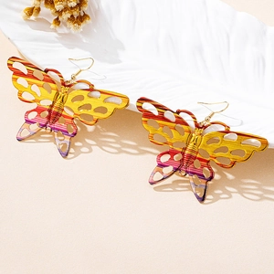 Close-up of oversized butterfly drop earrings with colorful gradient patterns
