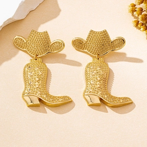 Macro view of vintage gold cowboy boot earrings with star relief and grainy metal texture