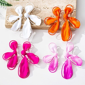 Close-up of matte geometric floral earrings in white, orange, and vibrant pink tones