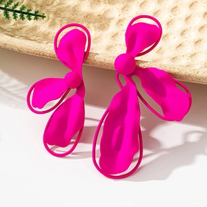 Detailed macro view of large matte fuchsia flower earrings with wavy layered petals