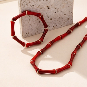 Detalle de conjunto de collar y pulsera de cuentas de bambú rojas con acentos dorados en piedra