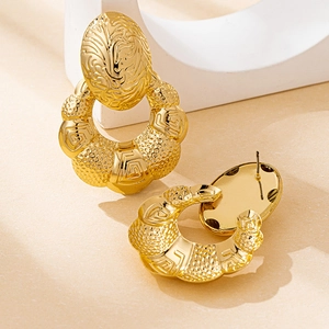 Detailansicht der goldenen geometrischen Muschel-Ohrringe mit Vintage-Prägung