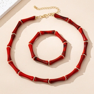 Detalle de cuentas de bambú rojo con separadores dorados en un conjunto de collar y pulsera