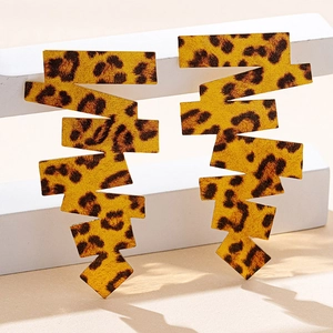 Dettaglio di orecchini a cerchio leopardati con design a zigzag su un piedistallo bianco
