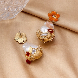 Detail of baroque pearl drop earrings with orange enamel flowers on golden satin