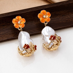 Macro view of gold flower earrings with orange enamel, baroque pearl and tulip detail