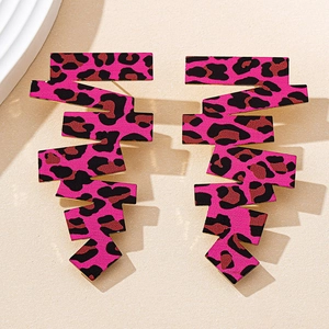 Dettaglio di orecchini geometrici leopardati rosa su sfondo beige materico beige