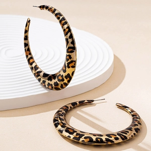 Dettaglio di grandi orecchini a cerchio leopardati con finitura dorata lucida e perni in argento