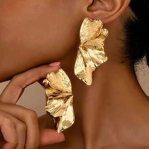 Dettaglio di grandi orecchini a fiore in oro martellato con trame metalliche a petalo