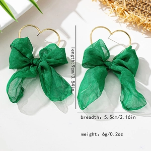 Dettaglio di orecchini a fiocco in chiffon verde con cerchi a cuore dorati e dimensioni