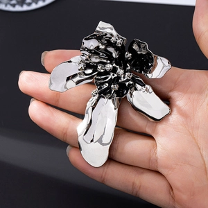 Polished silver floral brooch with black accents and rhinestones shown in hand
