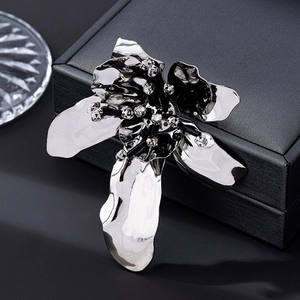 Macro view of silver floral brooch with diamond-encrusted black stamens and wavy petals