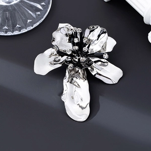 Detail showing high-gloss silver flower brooch with black rhinestone stamens on black backdrop