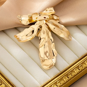 Detail of the golden flower brooch with hammered metal texture and secure back pin closure
