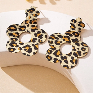Macro shot of yellow leopard print flower earrings on a white geometric display stand