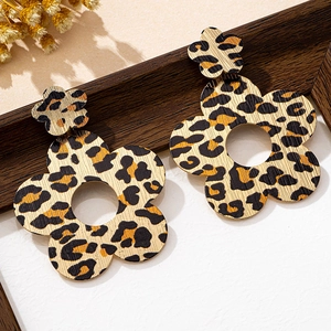 Detailed shot of layered leopard print flower earrings on a rustic wooden stand