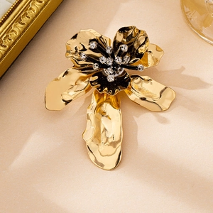 Detail of a golden flower brooch with hammered metal texture and sparkling crystal core