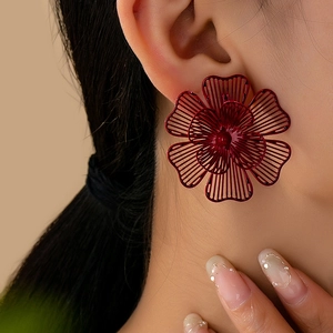 Vista detallada de pendientes de flores huecas en burdeos con pétalos de metal en capas