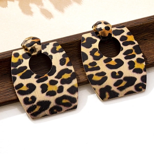 Detailed macro view of trapezoid leopard print earrings on elegant wooden stand