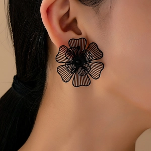 Primer plano de elegantes aretes de flor hueca en negro mate usados por una modelo