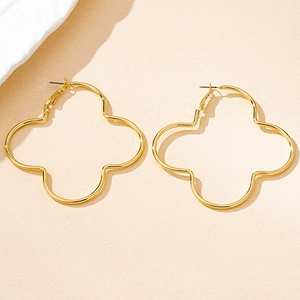 Detail of oversized gold clover hoop earrings with a hollow geometric petal design