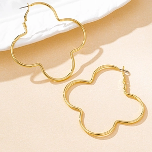 Detailed view of hollow four-leaf clover gold earrings with stylish camellia floral design