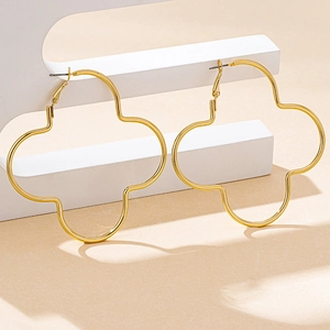 Detail view of large hollow gold quatrefoil clover earrings on geometric display stands