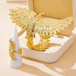 Close-up of golden phoenix rings with intricate feather engravings on a jewelry stand