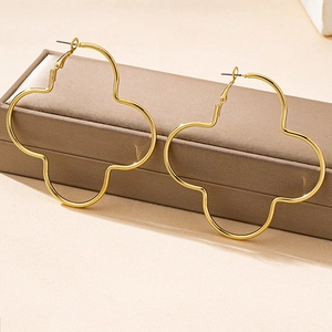 Detail view of large gold-toned clover hoop earrings on a leather jewelry box