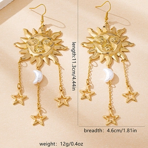 Detailed close-up of golden sun and moon tassel earrings with intricate celestial charms