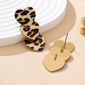Close-up of leopard print triple heart earrings with gold metal backing on a white tray