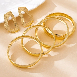 Detailed view of hammered gold bracelets and irregular textured earrings jewelry set