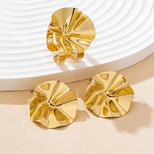 Detail showing gold floral textured ring and earrings on a white wavy display tray