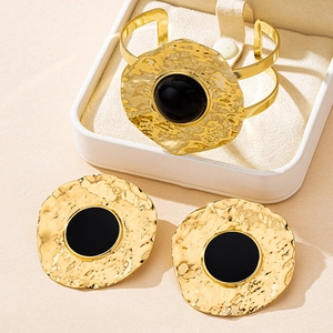Detailed view of gold hammered metal jewelry set with black round cabochon stones