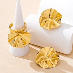 Detail of gold wavy irregular rings and earrings set on minimalist geometric display
