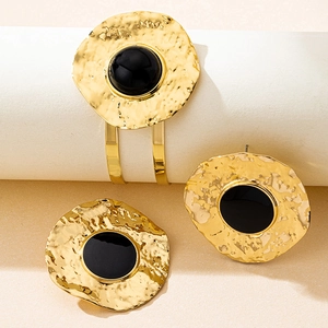 Detail of vintage golden hammered bangle and round stud earrings with black inlay inlay